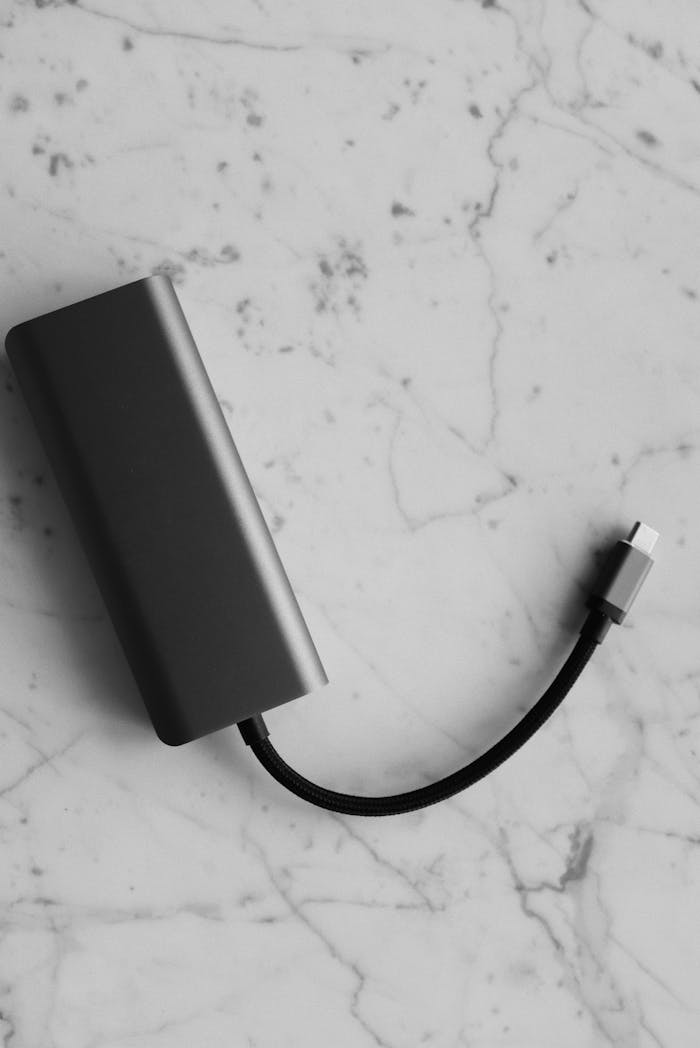 Black and white image of a power bank with cable on a marble surface.