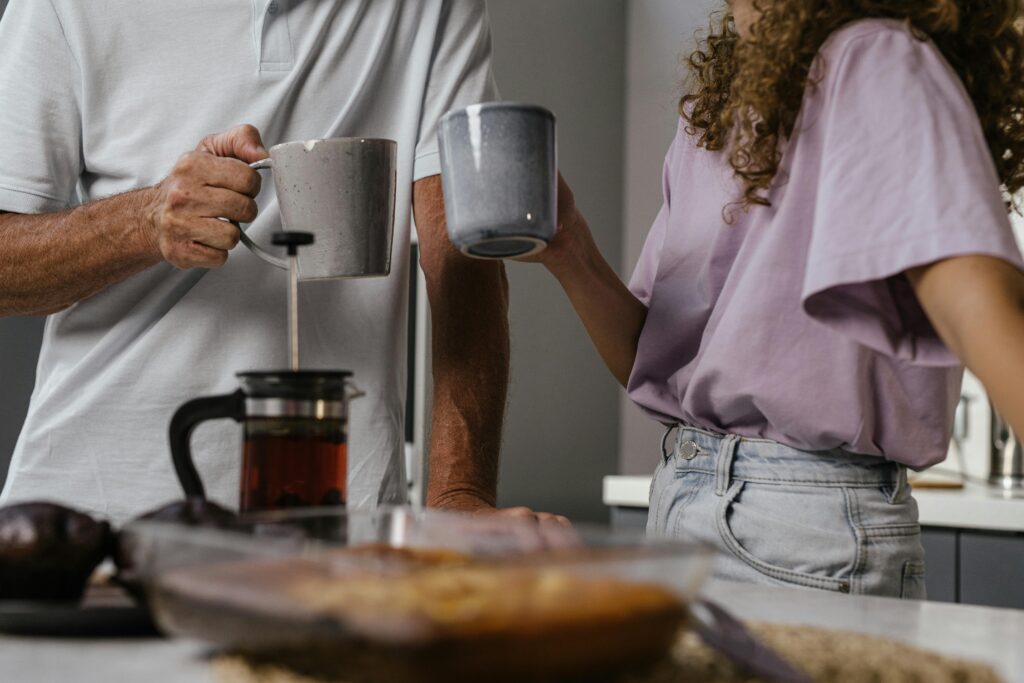 Couple enjoying a morning tea, holding mugs over a kitchen counter. Perfect start to a day.