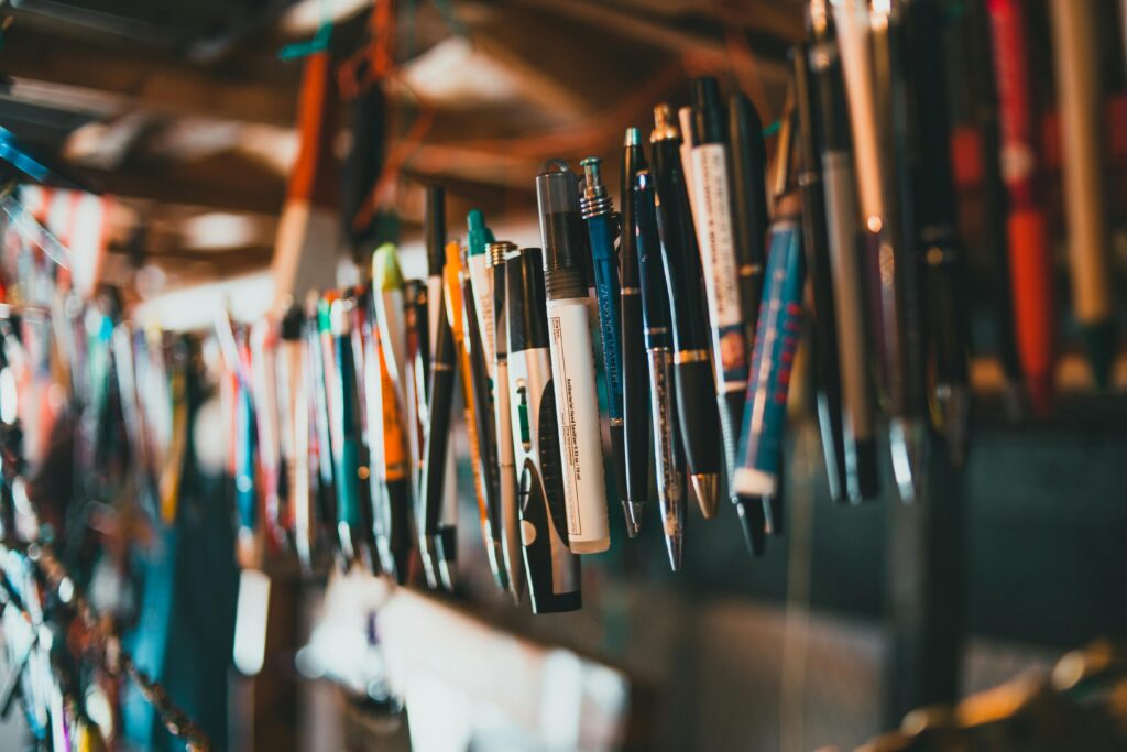 A creative display of assorted pens and markers hanging in a colorful shop setup.